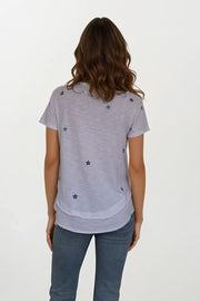 back view of woman wearing white mock layer t shirt with start details 