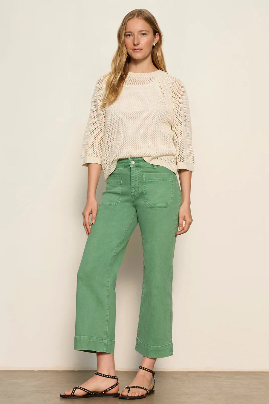 woman wearing a cream open-knit sweater with a relaxed fit and three-quarter sleeves, front