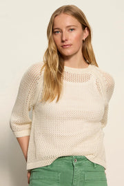 woman wearing a cream open-knit sweater with a relaxed fit and three-quarter sleeves, front