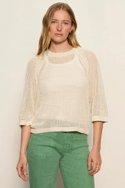 woman wearing a cream open-knit sweater with a relaxed fit and three-quarter sleeves, front