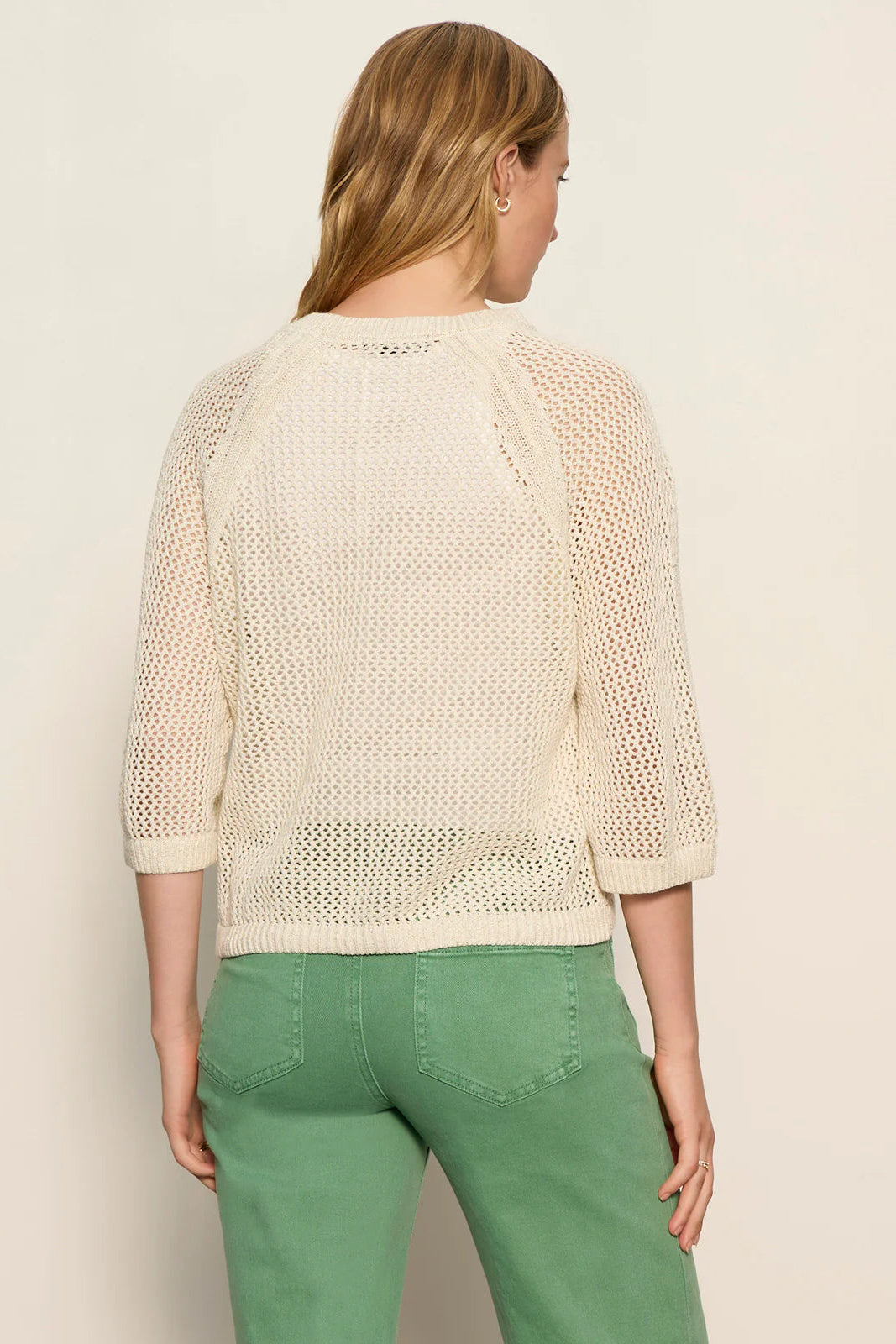 woman wearing a cream open-knit sweater with a relaxed fit and three-quarter sleeves, back