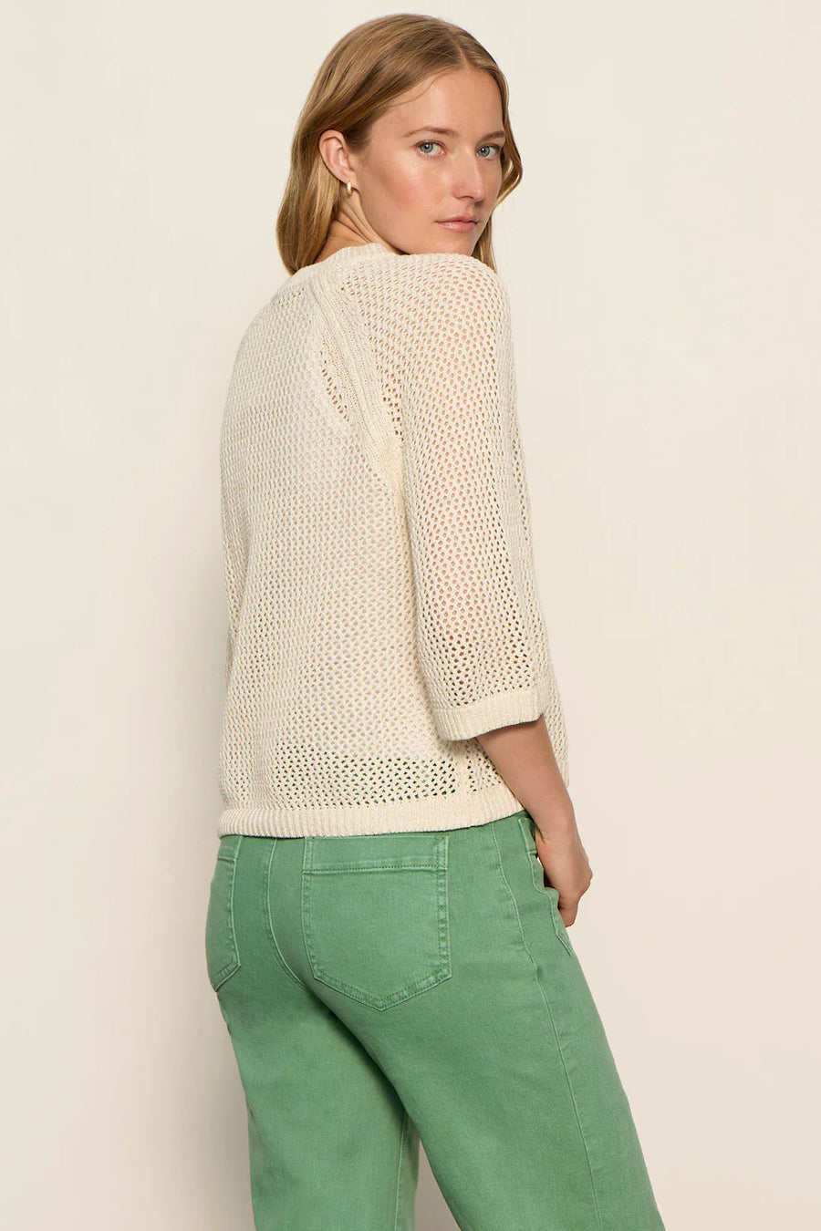 woman wearing a cream open-knit sweater with a relaxed fit and three-quarter sleeves, back