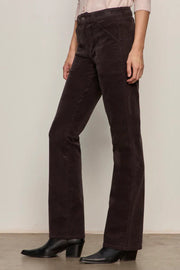 Person wearing dark brown corduroy pants against a plain background