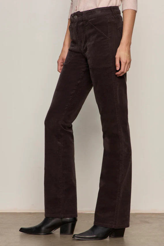 Person wearing dark brown corduroy pants against a plain background