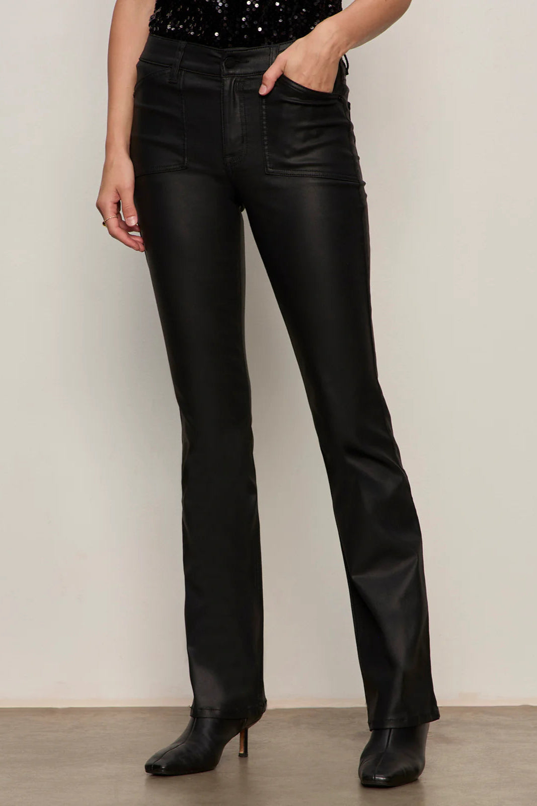 Person wearing black sculpted denim pants against a plain background
