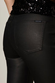 Close up of the back pockets of a person wearing black sculpted denim pants against a plain background