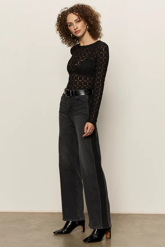 woman wearing washed black relaxed straight jean with lines on the sides and black textured tee
