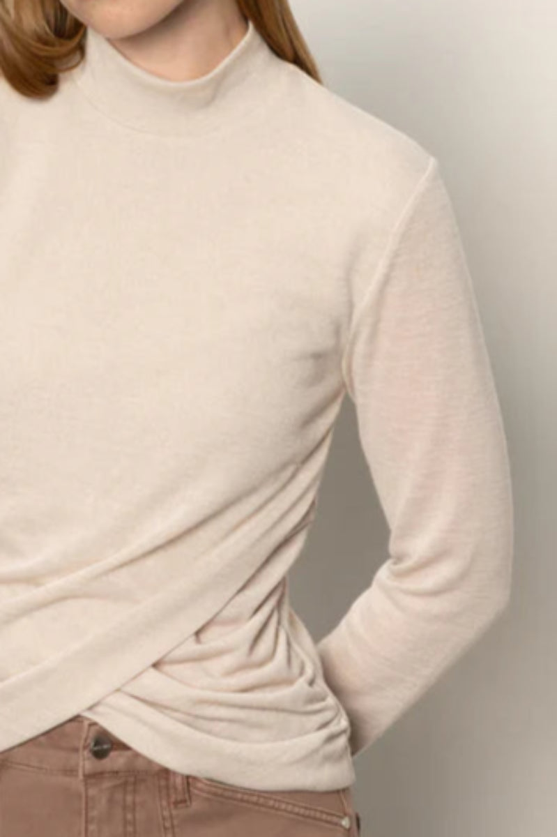 Close-up of woman wearing a beige long-sleeve top with rouching in both sides