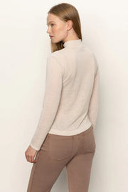 Back view of woman wearing a beige long-sleeve top with rouching in both sides