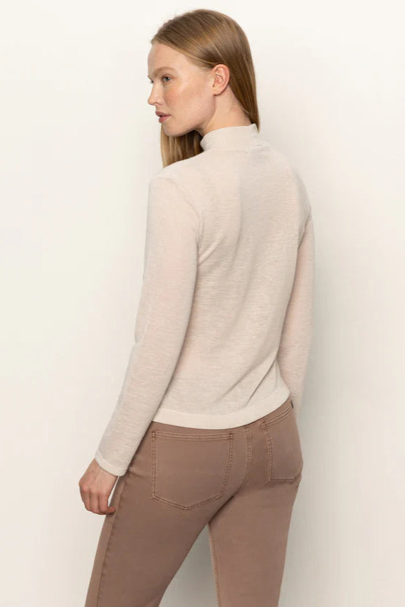 Back view of woman wearing a beige long-sleeve top with rouching in both sides