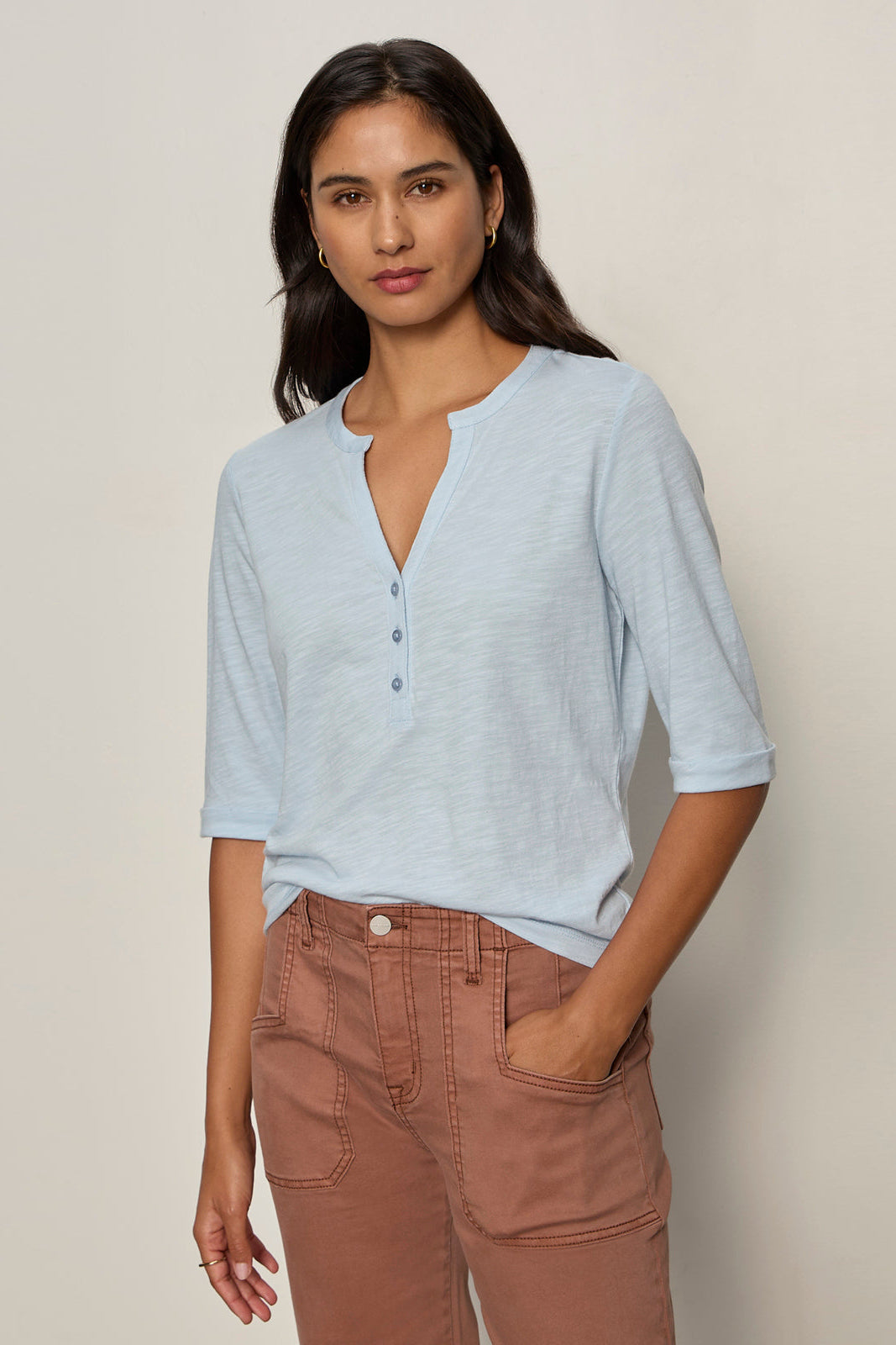 woman wearing a baby blue 3 button v neck with rolled sleeves