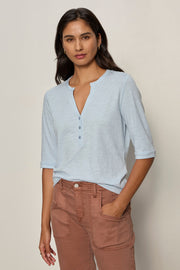 woman wearing a baby blue 3 button v neck with rolled sleeves