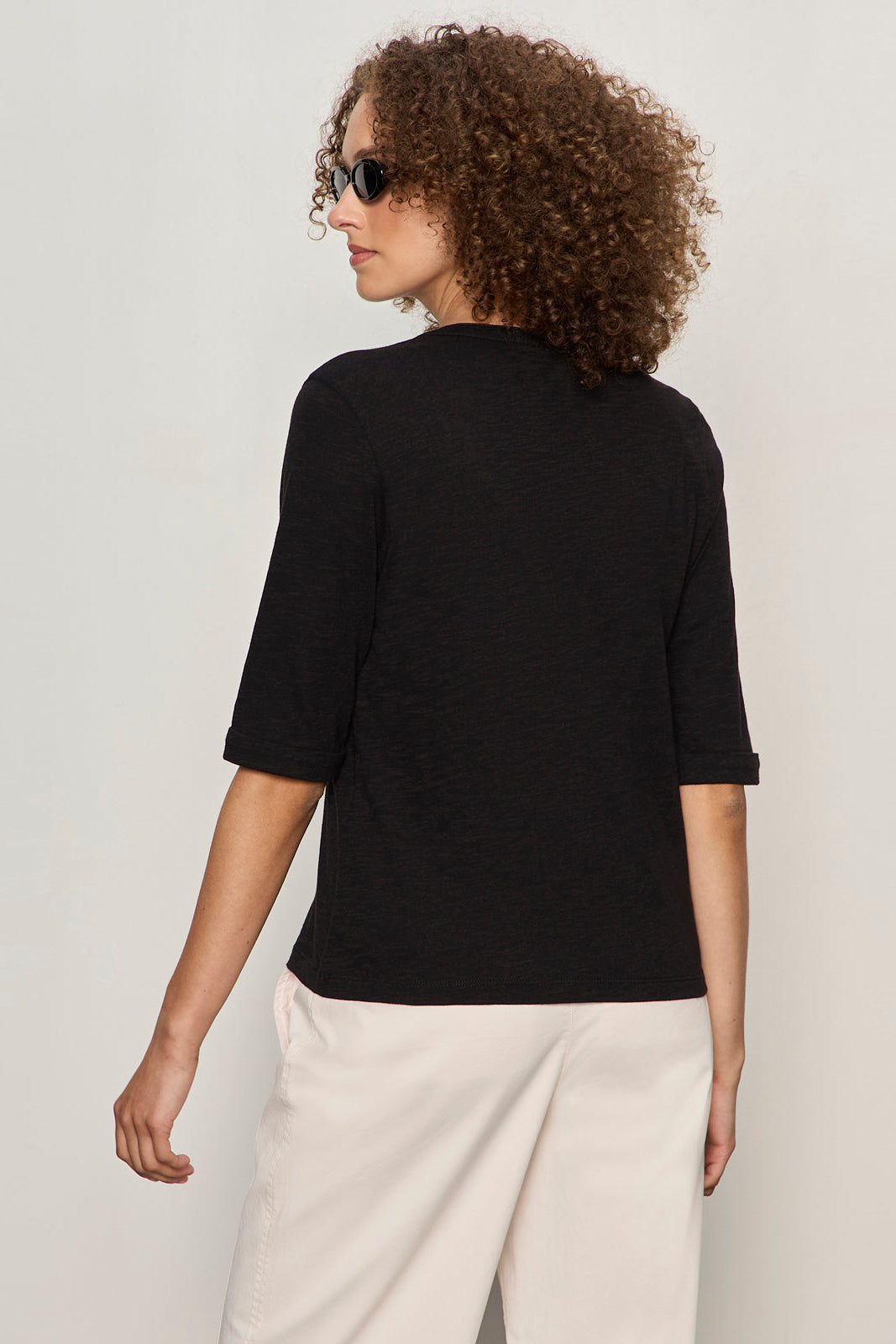 back view of black 3 button v neck with rolled sleeves