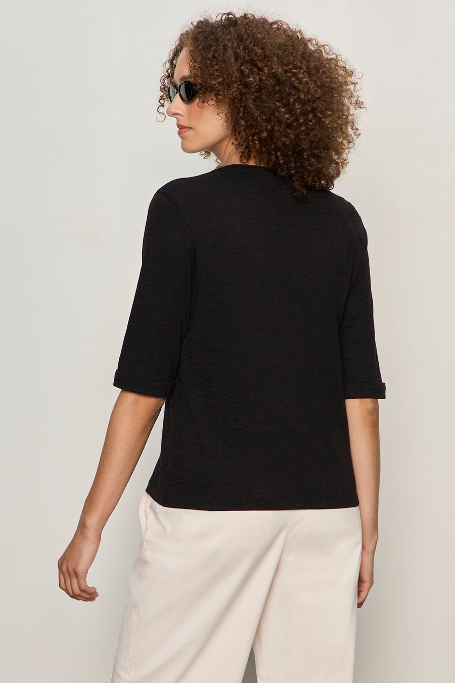 back view of black 3 button v neck with rolled sleeves