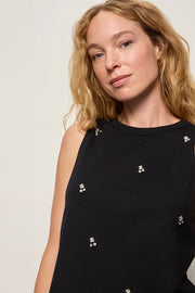 Woman wearing a black sleeveless top with embellished details 