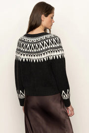 Woman wearing a black sweater with white pattern on a plain background
