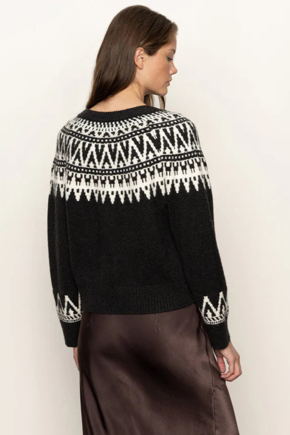 Woman wearing a black sweater with white pattern on a plain background