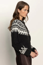 Woman wearing a black sweater with white pattern on a plain background
