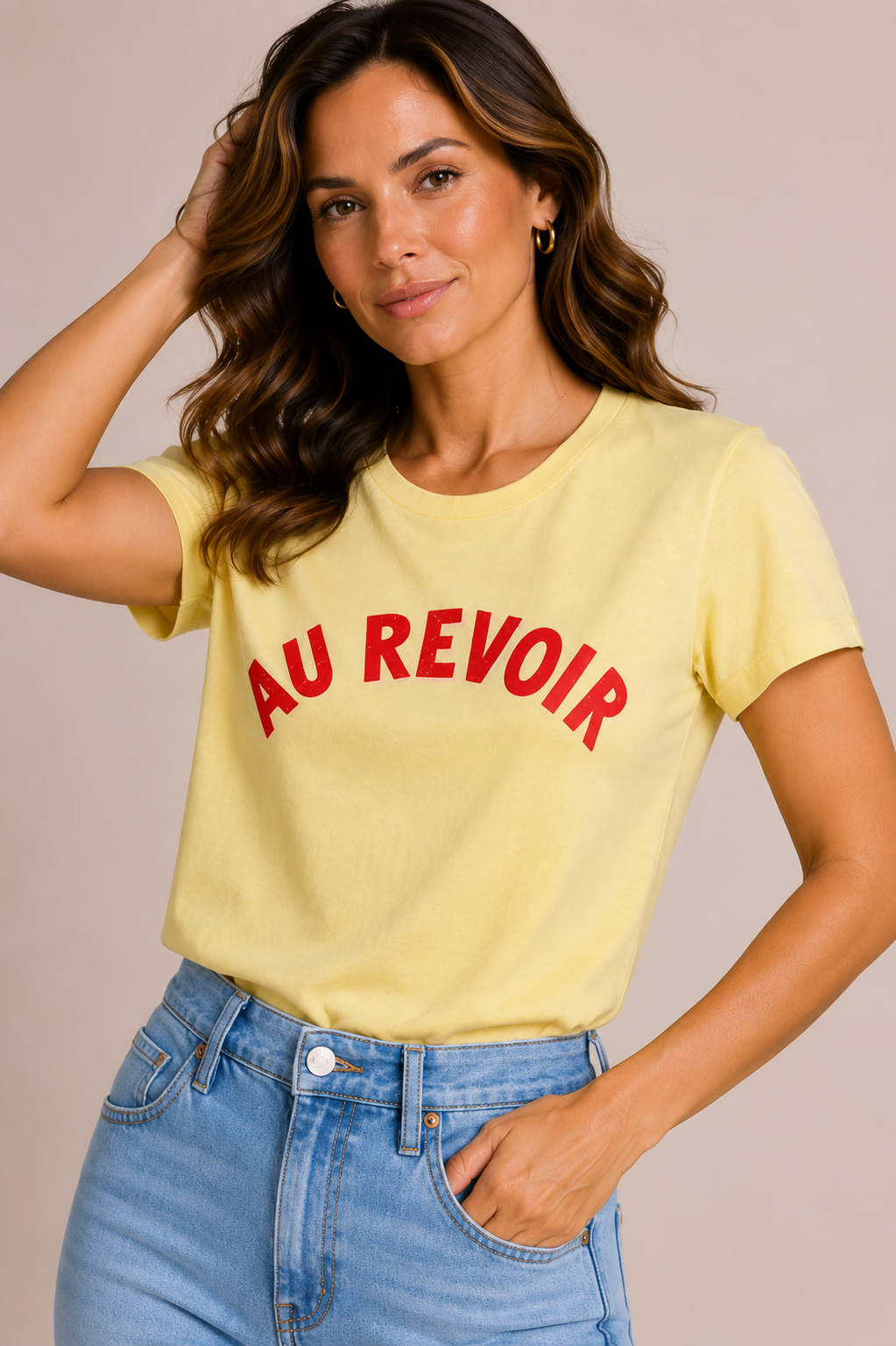 Woman wearing a butter yellow t-shirt with 'AU REVOIR' in pink text