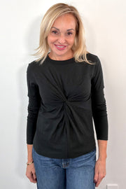 Woman wearing a black long-sleeve top with a knot detail 