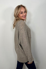 Side view of woman wearing a greige asymmetrical sweater 