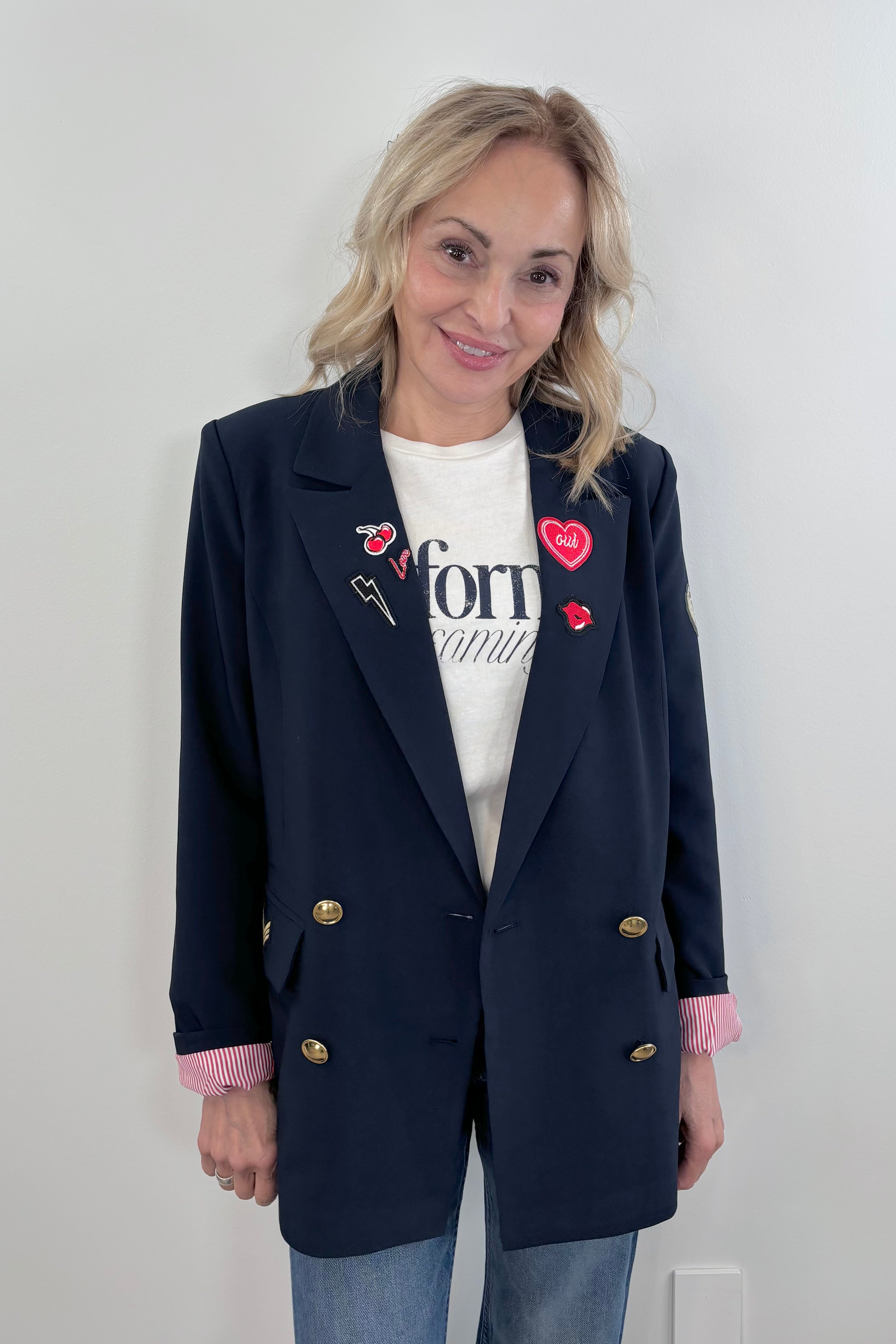 Woman wearing a navy blue blazer with gold buttons and patch details