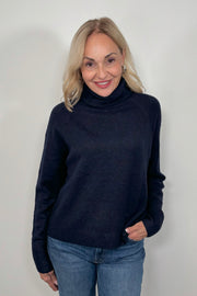 Front view of woman wearing an oversized Navy knitted turtleneck 