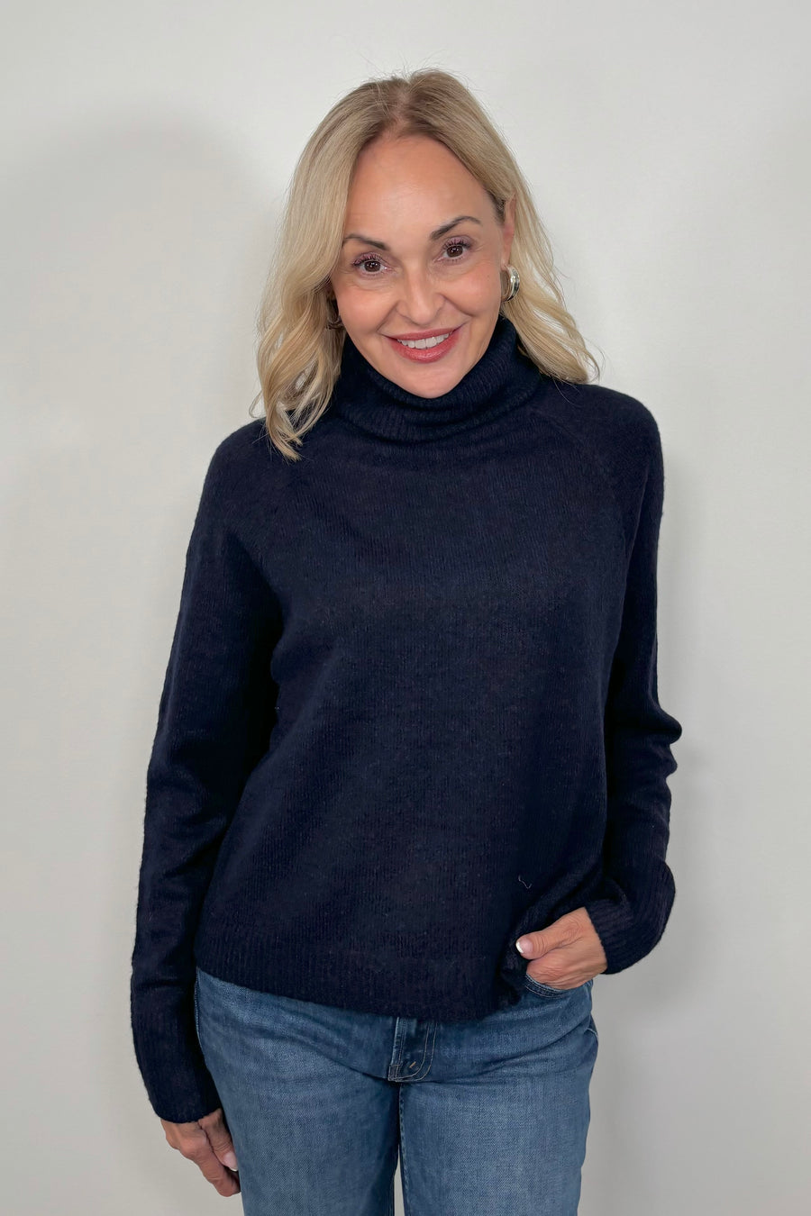 Front view of woman wearing an oversized Navy knitted turtleneck 