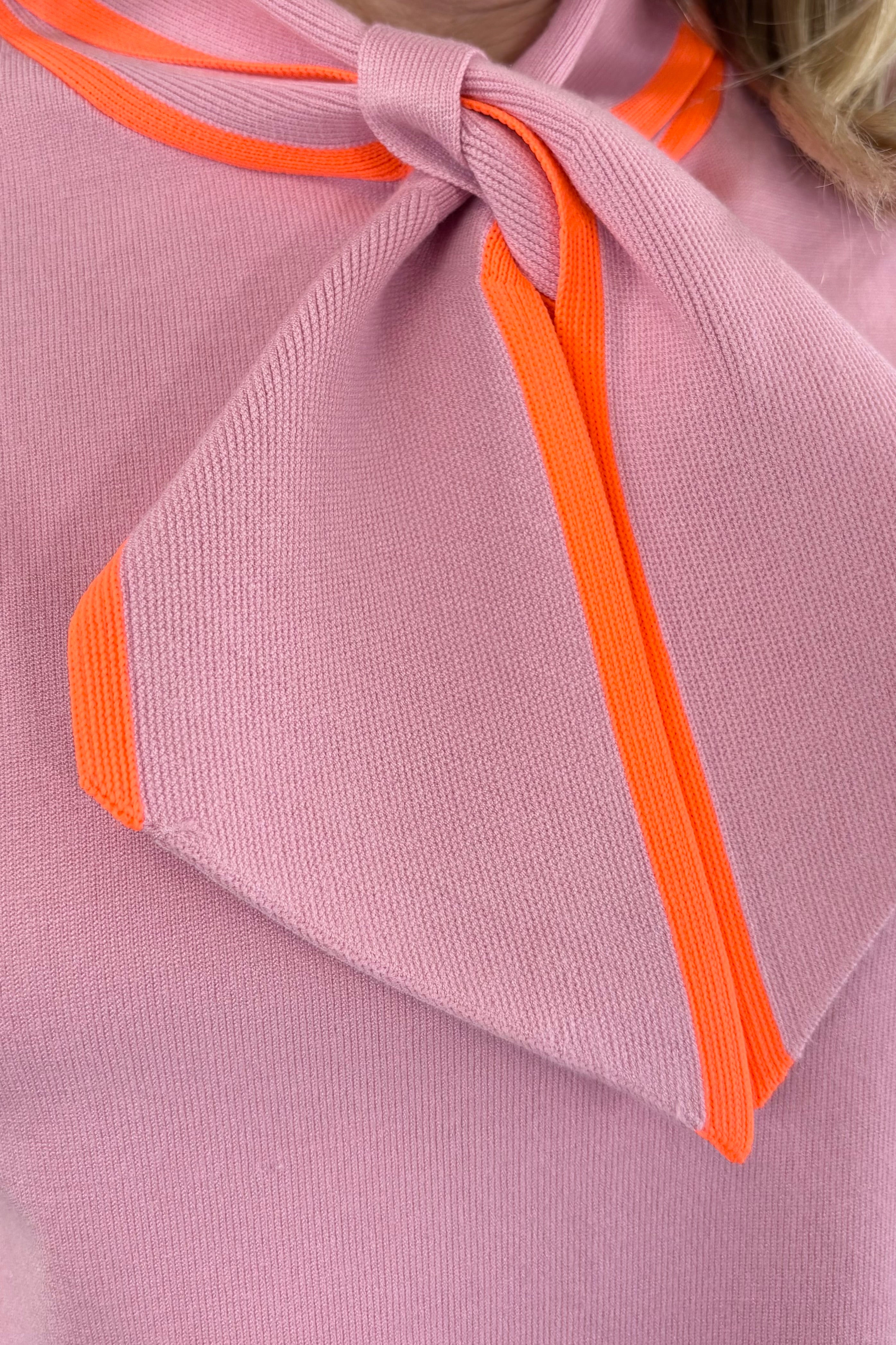 Close up of Woman wearing a light pink neck tie top with orange accents
