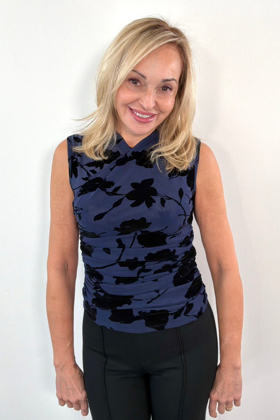 Woman wearing a sleeveless navy mesh top with black floral pattern 