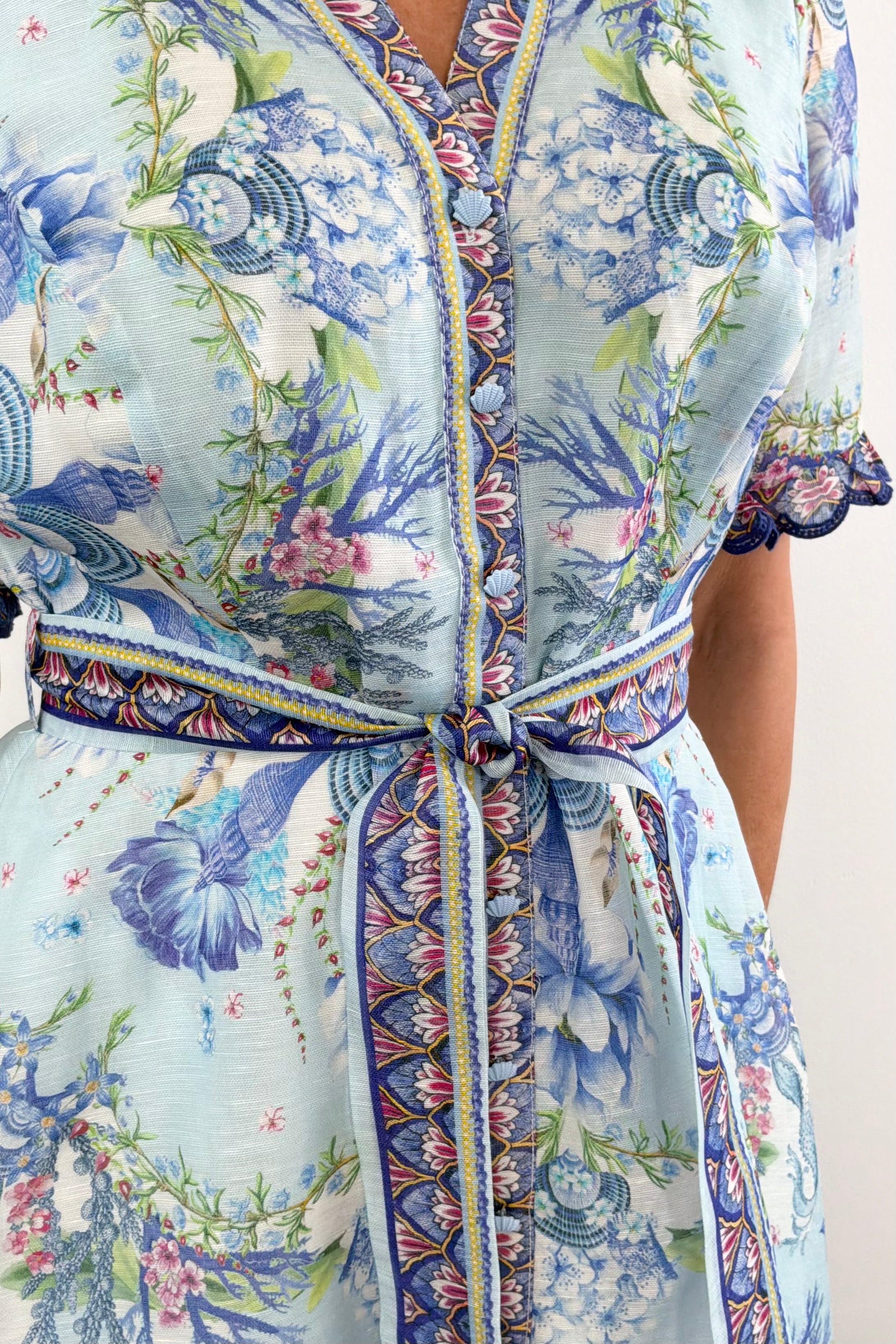 Woman wearing a long blue floral dress with detailed sleeves 