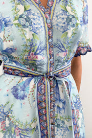Woman wearing a long blue floral dress with detailed sleeves 