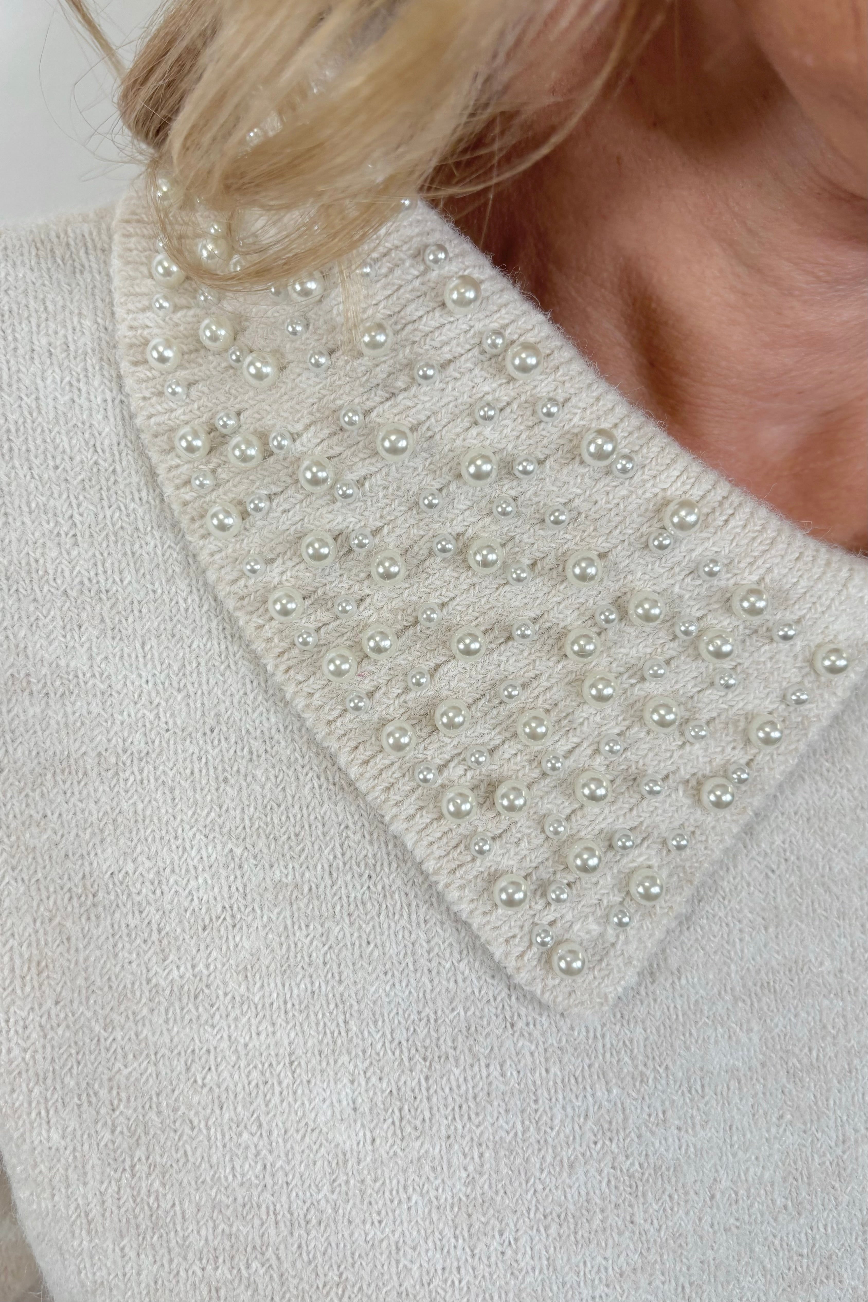 close-up of an off white collard sweater with pearl detailing 