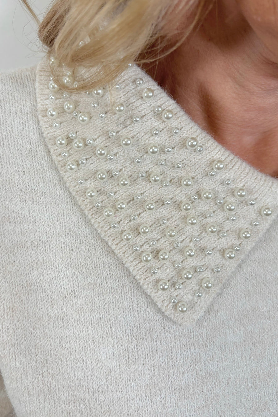 close-up of an off white collard sweater with pearl detailing 