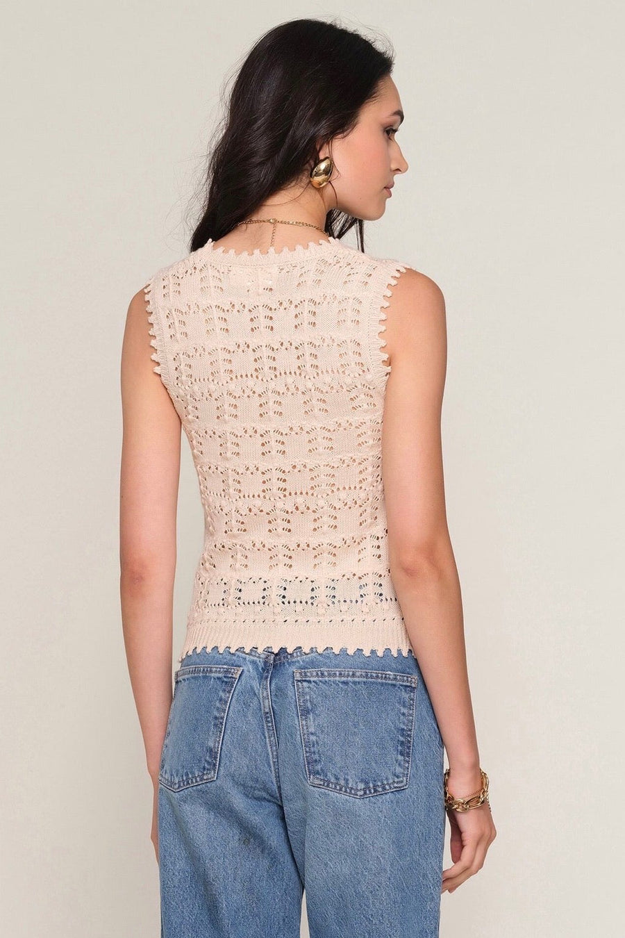 Back view of Woman wearing a light beige knit vest with button up detail
