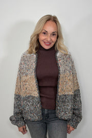 Front view of woman wearing a light gray, beige and dark gray knitted cardigan