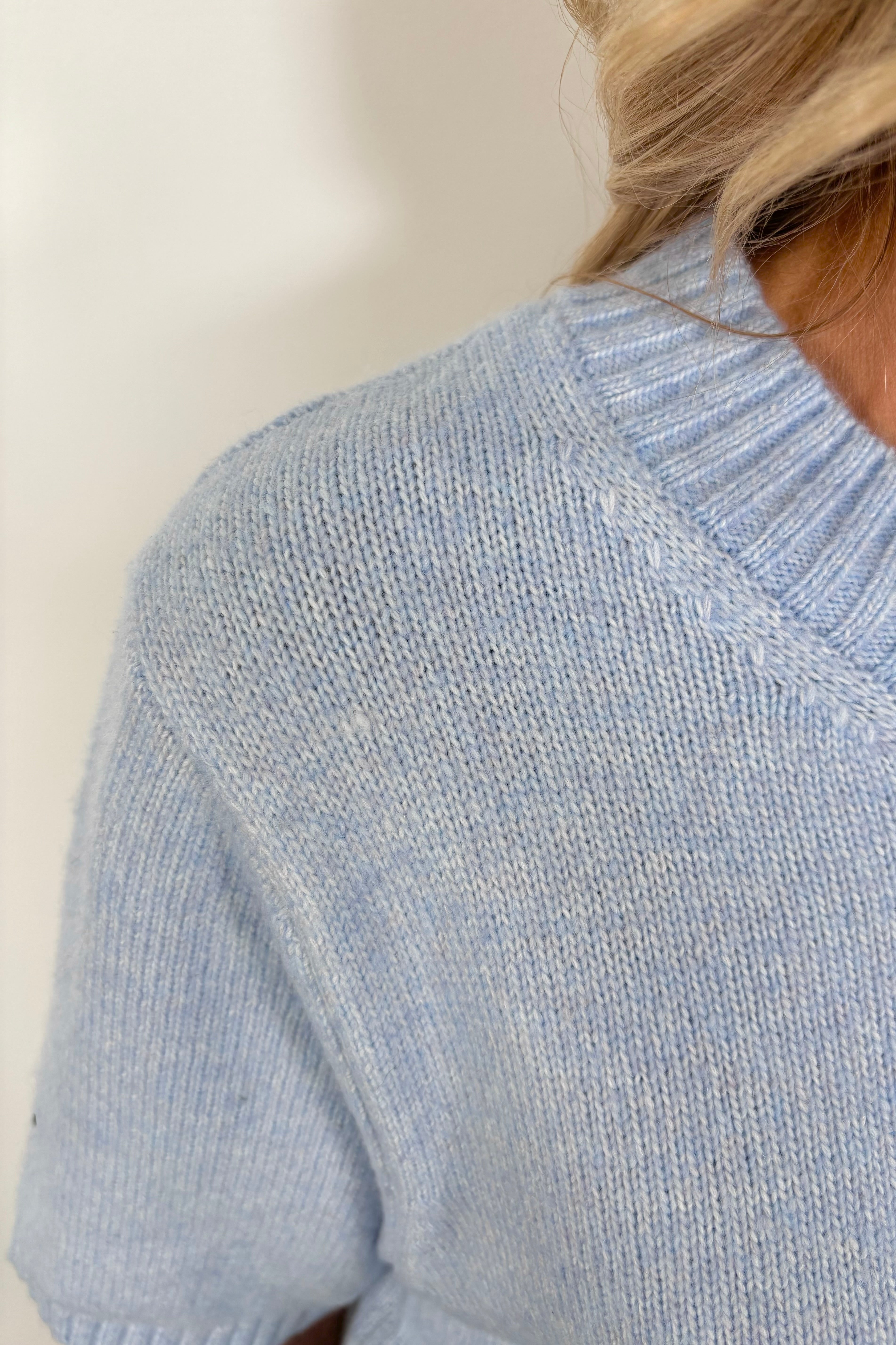 Close up view of woman wearing a light blue half sleeve sweater’s collar