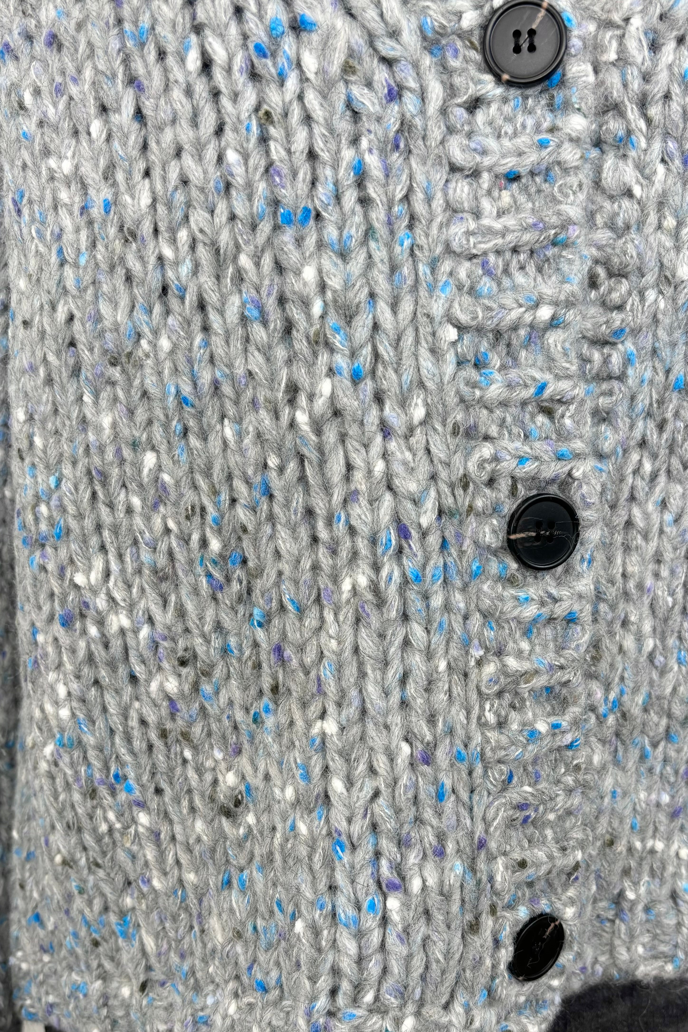 Close up of the buttons of a blue and gray cardigan