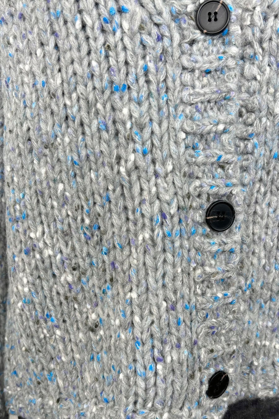 Close up of the buttons of a blue and gray cardigan