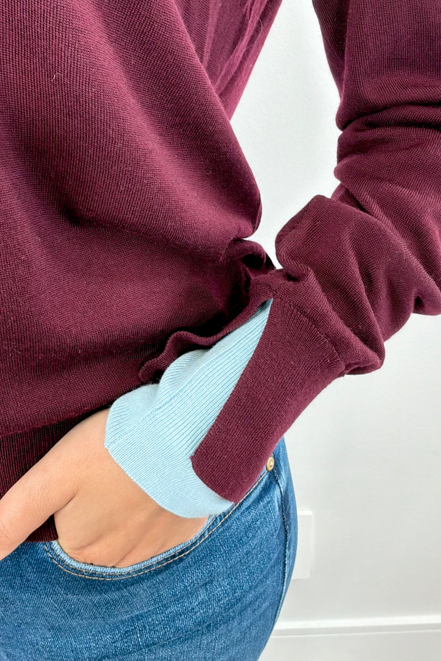 Woman wearing a burgundy sweater with a blue collar