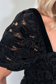 Black lace dress with floral patterns on a plain background