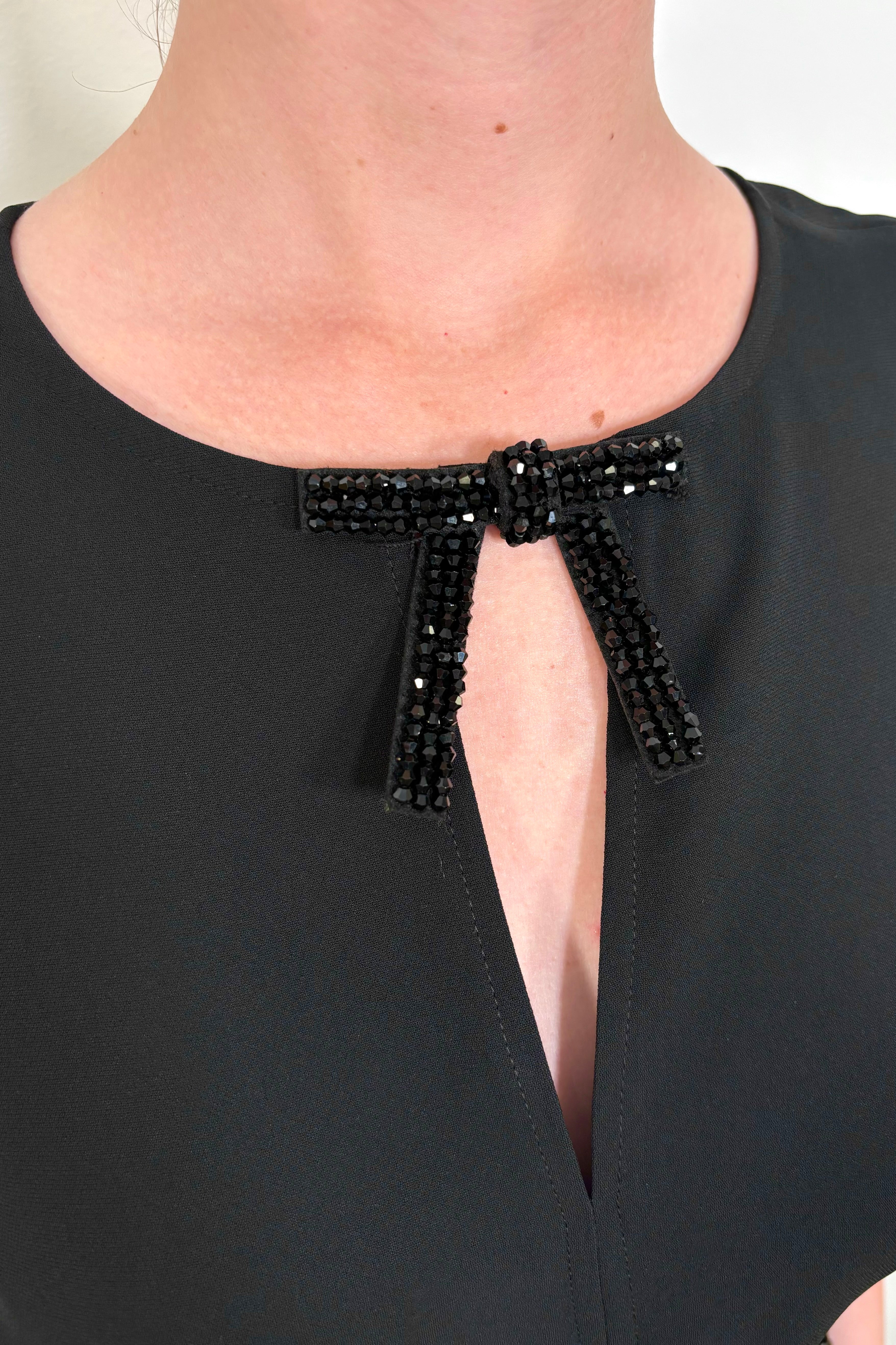 Close-up of a black tank top with crystal bow detailing