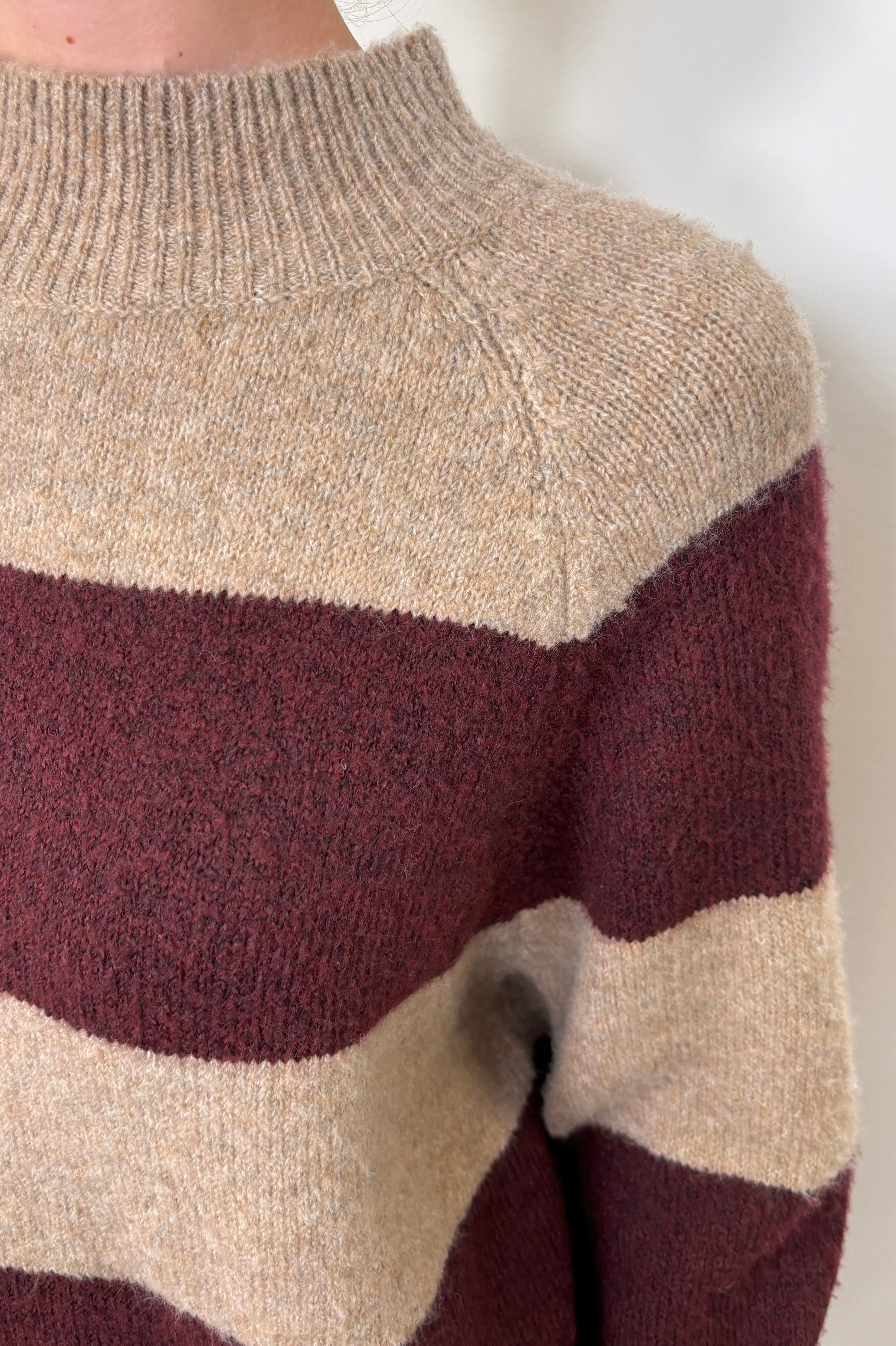 Close-up of a woman wearing a Sweater with burgundy stripes 