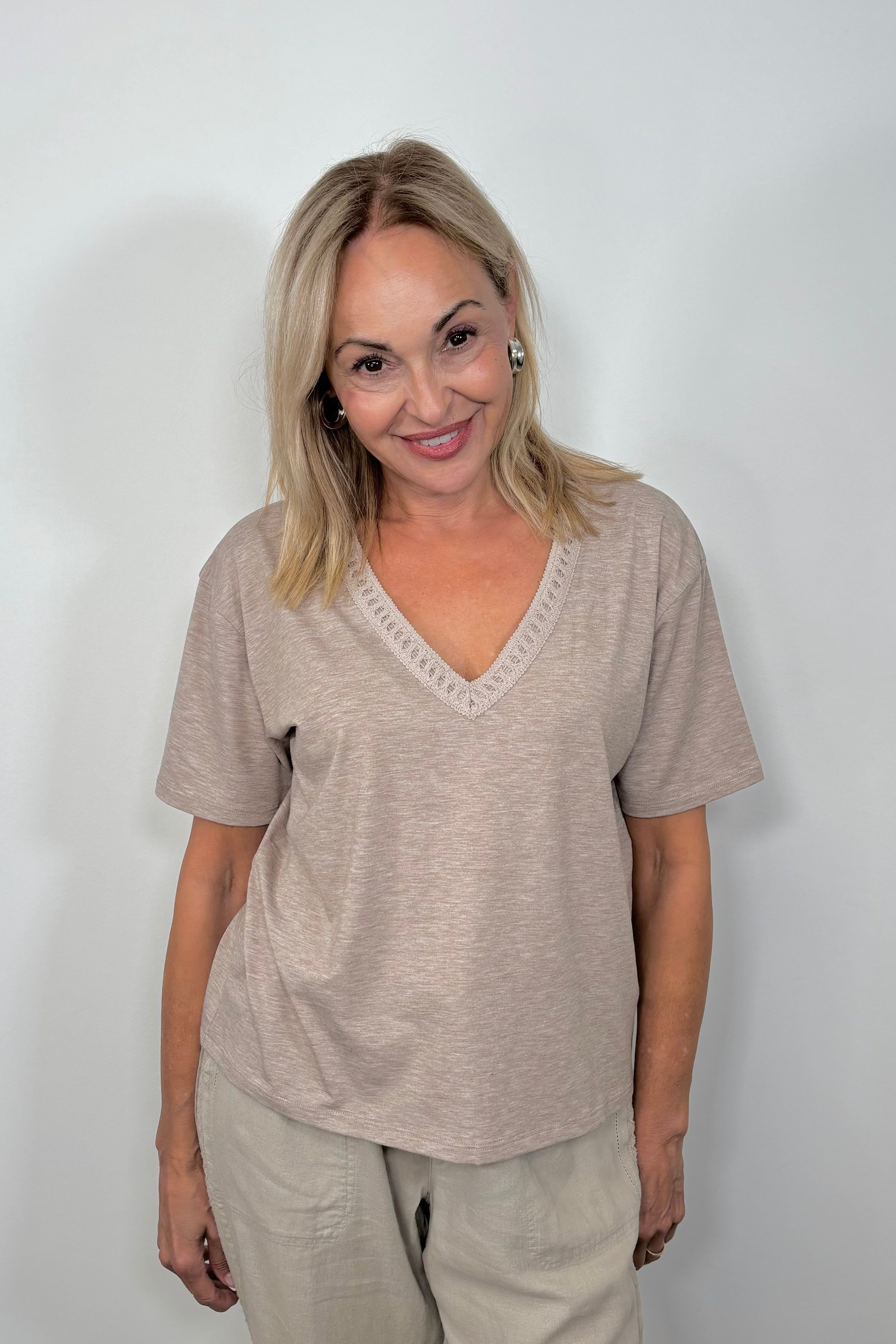 Front view of woman wearing a cool beige v-neck tee