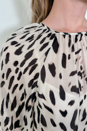 Close up view of woman wearing a sheer printed blouse with a cami underneath