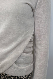 close-up of a woman wearing a light long sleeve draped beck top