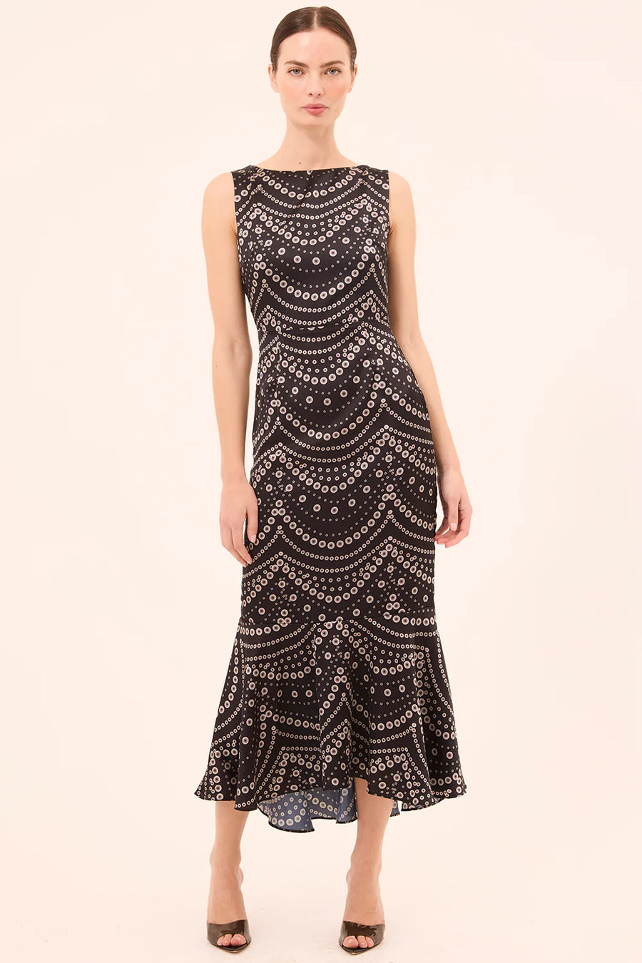 Woman wearing a black patterned dress on a beige background