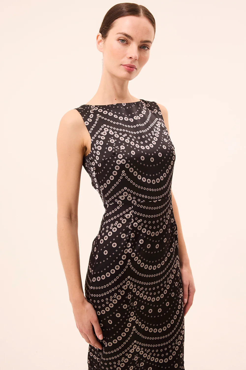 Woman wearing a black dress with a pattern on a beige background