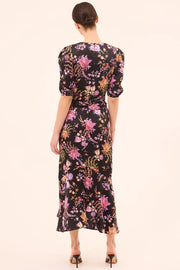 Woman wearing a floral dress with puff sleeves on a plain background