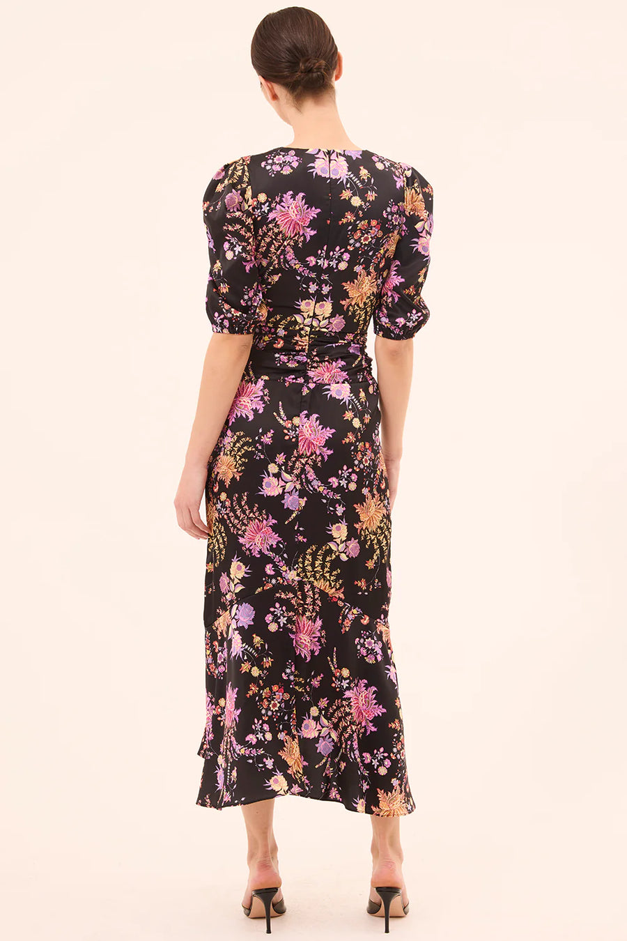 Woman wearing a floral dress with puff sleeves on a plain background